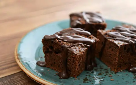 Saftige Brownies, perfekt für ein schnelles Brownie Rezept. Mit flüssiger Schokolade übergossen und auf einem türkisfarbenen Teller angerichtet.