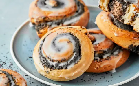Saftige Mohnschnecken mit Zuckerguss auf einem blauen Teller. Dieses Bild inspiriert zum Nachbacken mit einem einfachen Mohnschnecken Rezept.
