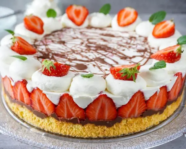 Eine köstliche Erdbeer Mascarpone Torte mit frischen Erdbeeren, Sahnetupfern und Schokoladendekor.