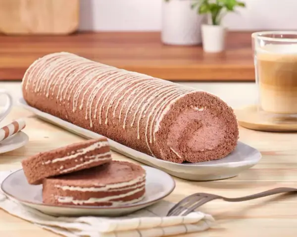 Eine köstliche schoko biskuitrolle mit weißer Glasur, dane zwei Scheiben und ein Kaffee.