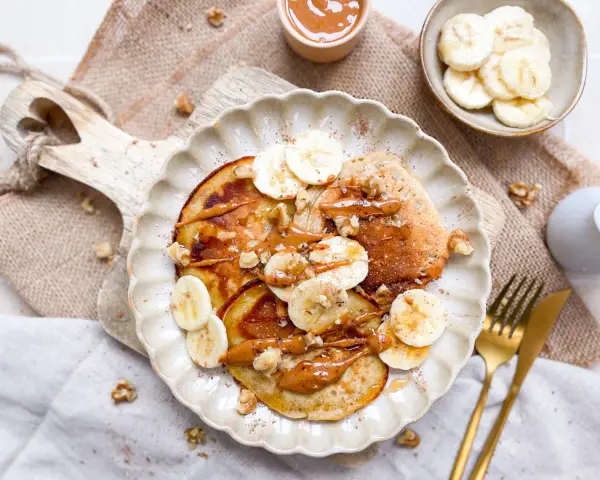 Leckere bananen pancakes ohne ei, garniert mit Bananenscheiben, Nüssen und einer cremigen Sauce. Ein Genuss für jeden Morgen!