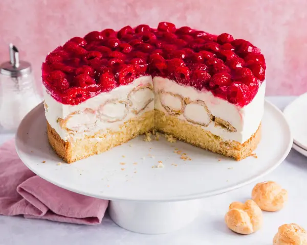Eine köstliche Windbeutel Torte mit frischen Himbeeren und Sahne. Kleine Windbeutel sind in die cremige Füllung eingebettet.