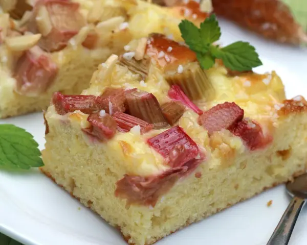 Saftiger Rhabarberkuchen mit cremiger Füllung, perfekt für Rhabarber Rezepte. Mit Minze garniert.