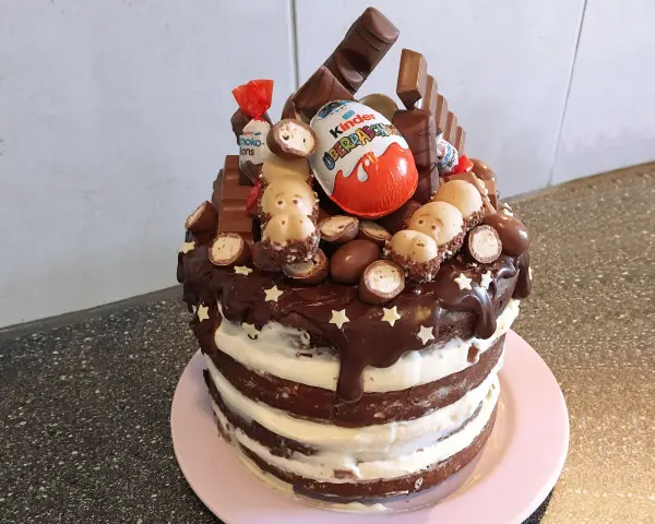 Schokoladentorte mit Kinder-Überraschungsei, Schoko-Bons und vielen weiteren Süßigkeiten dekoriert.