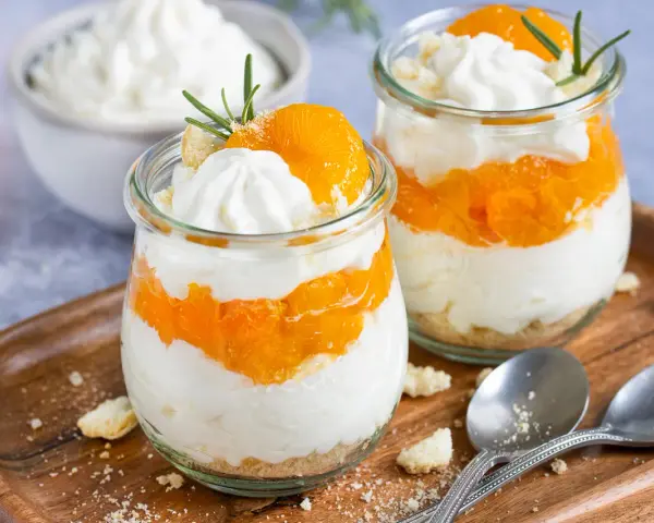 Zwei Gläser mit einem schnellen Dessert aus Mandarinen und Sahne, garniert mit Rosmarin.