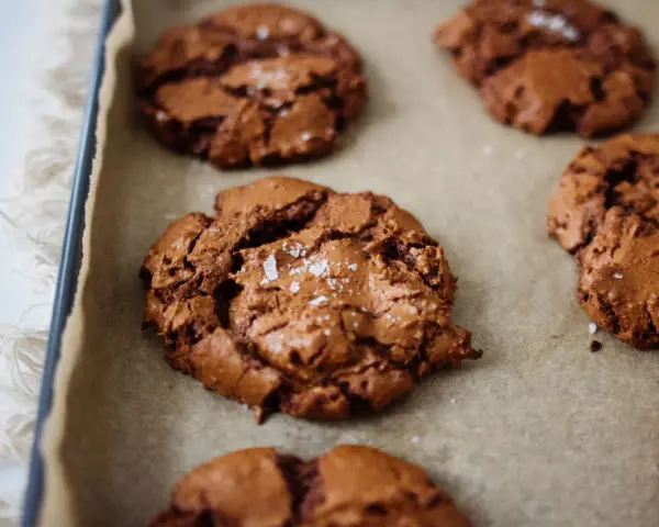 Saftige schoko cookies mit Meersalzflocken auf Backpapier, bereit zum Genießen.