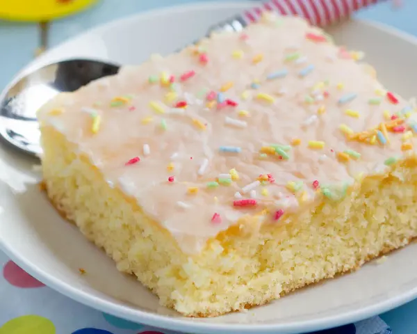 Ein Stück saftiger Fantakuchen mit Zuckerguss und bunten Streuseln, perfekt für das Fantakuchen Rezept.
