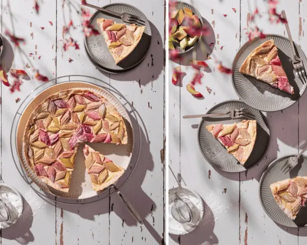 Ein köstlicher Rhabarberkuchen mit Pudding, kunstvoll arrangiert mit frischen Rhabarberstücken und Puderzucker bestäubt.