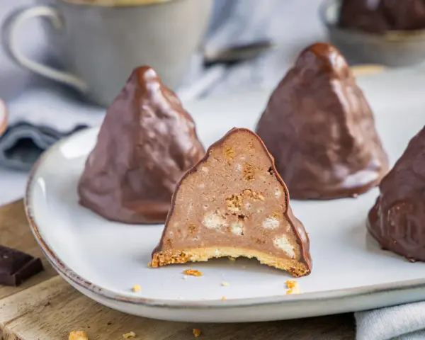Schokoladen-Desserts, die an Granatsplitter erinnern, mit einem Stück, das die cremige Füllung mit Keksstücken zeigt. Ein köstliches granatsplitter rezept.