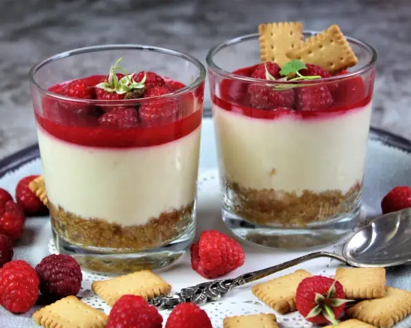 Zwei leckere Desserts im Glas mit Himbeeren und Keksen, ein süßer Genuss.