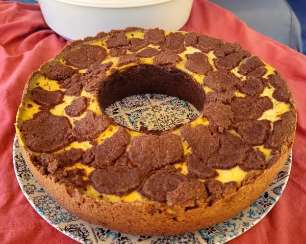 Ein köstlicher russischer Zupfkuchen mit einem Mürbeteigboden und einer cremigen Käsemasse, bedeckt mit schokoladigen Zupfen.