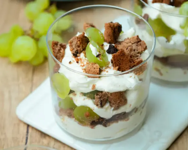 Cremiges Dessert im Glas mit grünen Trauben und zerbröselten Keksen. Ein süßer Genuss, der an einen Trauben-Keks-Traum erinnert.