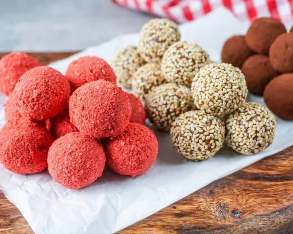 Drei Sorten leckere Energy Balls: rote Erdbeer-Bällchen, mit Sesam umhüllte Kugeln und schokoladige Trüffel.