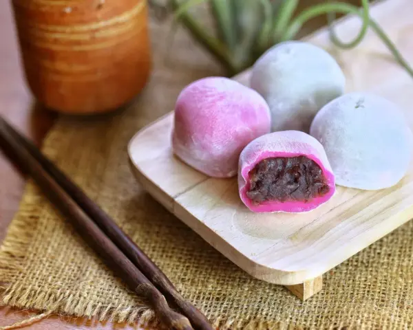 Bunte Mochi-Kugeln mit roter Bohnenpaste, bereit zum Genießen. Perfekt, um Mochi selber machen zu lernen und diese Leckereien zu kreieren.