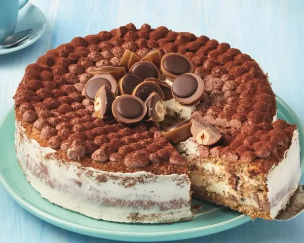 Eine köstliche Toffifee Torte, verziert mit Kakao und Toffifee-Pralinen, wird angeschnitten.