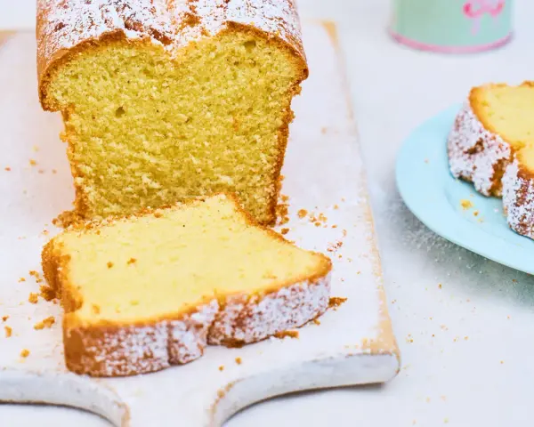 Ein saftiger Sandkuchen, bestäubt mit Puderzucker, wartet darauf, nach diesem einfachen Sandkuchen Rezept gebacken zu werden.