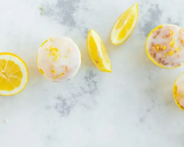 Erfrischende Zitronenmuffins mit Zuckerguss und Zitronenspalten. Ein tolles Rezept für zitronenmuffins!