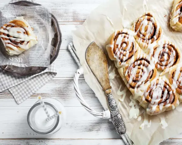 Frisch gebackene schwedische Zimtschnecken mit Zuckerguss, serviert mit einem Glas Milch.