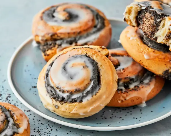 Saftige Mohnschnecken mit Zuckerguss auf einem blauen Teller. Dieses Bild inspiriert zum Nachbacken mit einem einfachen Mohnschnecken Rezept.
