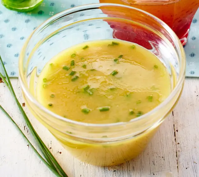 Ein Glas mit cremigem honig senf dressing, garniert mit Schnittlauch. Perfekt für Salate.