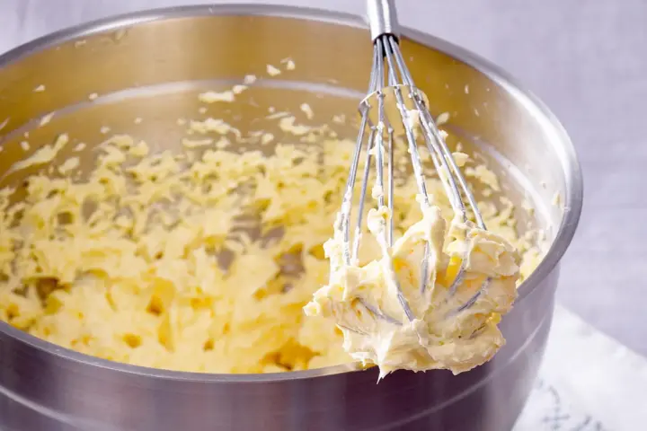 Ein Schneebesen mit cremigem Teig, bereit für ein Buttercreme Rezept.