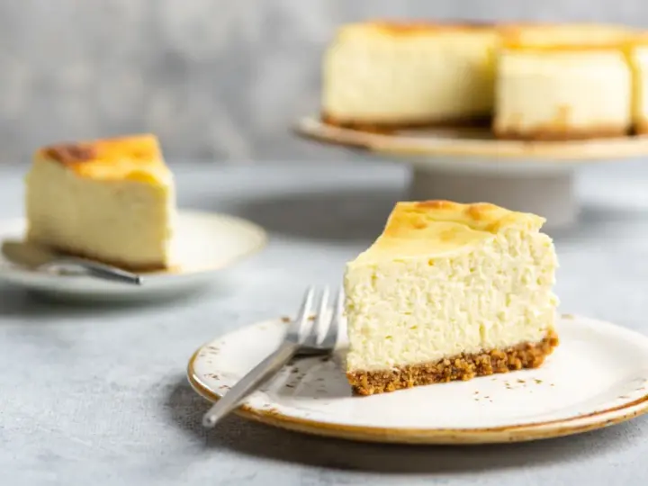Ein cremiger Kuchen mit Mascarpone, auf einem Teller mit Gabel, daneben ein weiteres Stück und ein ganzer Kuchen.