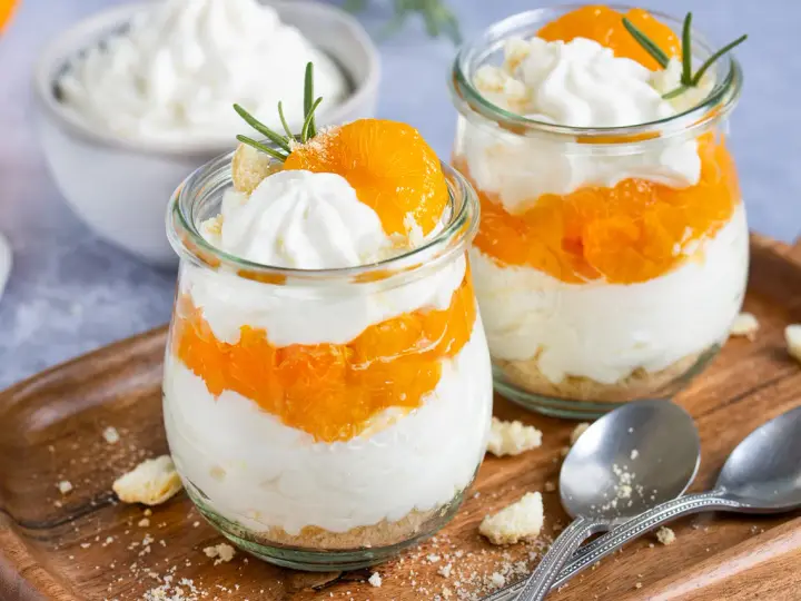 Zwei Gläser mit einem schnellen Dessert aus Mandarinen und Sahne, garniert mit Rosmarin.