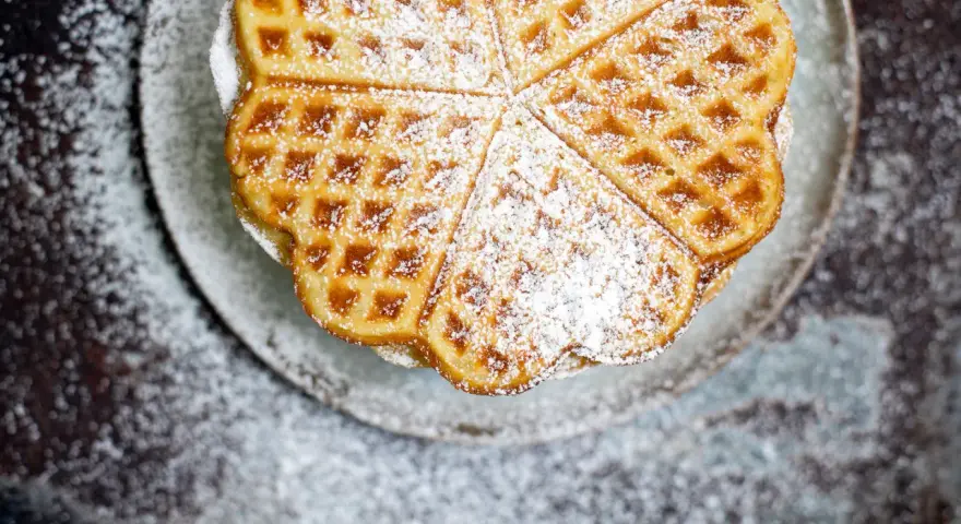 Herzförmige Bananenwaffeln, bestäubt mit Puderzucker, auf einem Teller. Ein süßer Genuss für jeden Tag.