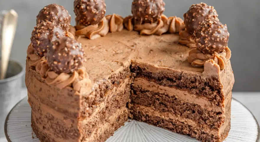 Schokoladige nougat torte mit Ferrero Rocher Kugeln und zarter Schokoladencreme. Ein Stück fehlt bereits.