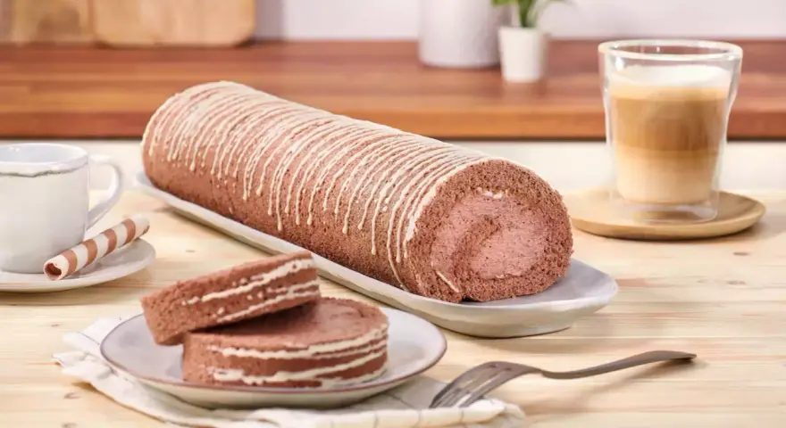 Eine köstliche schoko biskuitrolle mit weißer Glasur, dane zwei Scheiben und ein Kaffee.