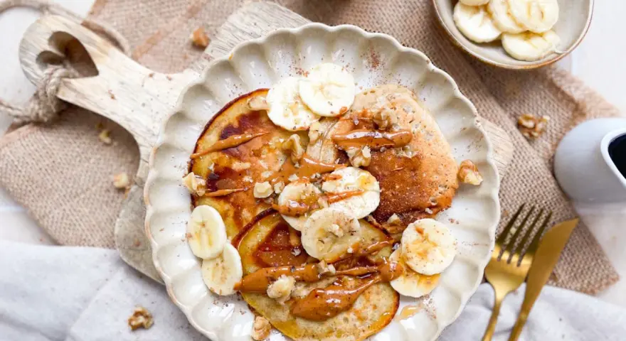 Leckere bananen pancakes ohne ei, garniert mit Bananenscheiben, Nüssen und einer cremigen Sauce. Ein Genuss für jeden Morgen!