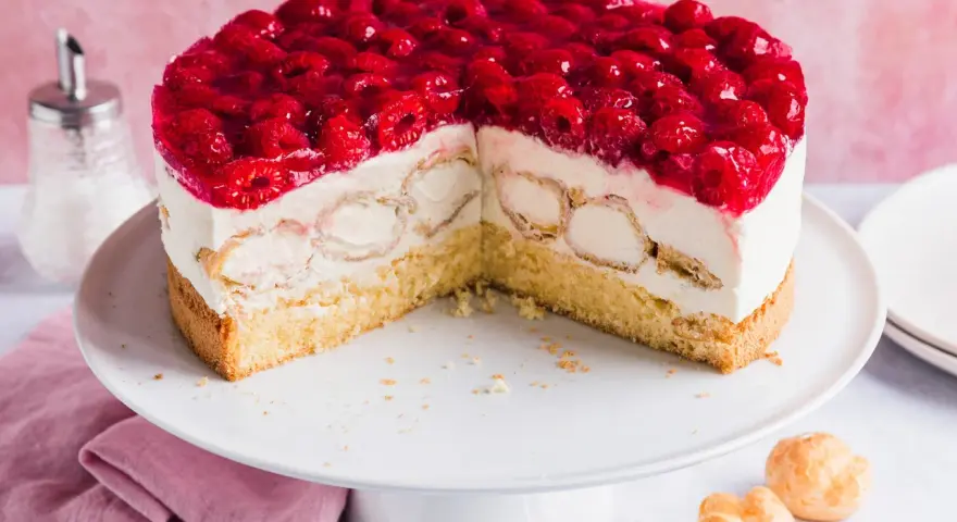 Eine köstliche Windbeutel Torte mit frischen Himbeeren und Sahne. Kleine Windbeutel sind in die cremige Füllung eingebettet.