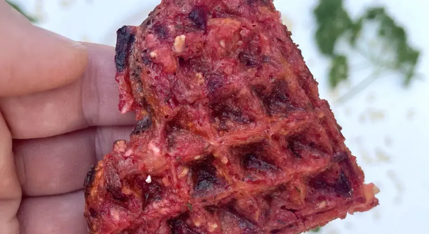 Herzhafte Waffeln aus Roter Bete, gehalten von einer Hand. Ein gesunder Snack mit leckerer Textur.