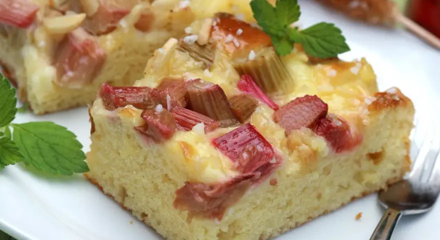 Saftiger Rhabarberkuchen mit cremiger Füllung, perfekt für Rhabarber Rezepte. Mit Minze garniert.