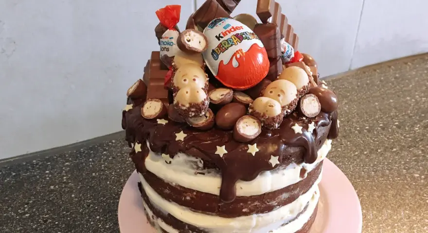 Schokoladentorte mit Kinder-Überraschungsei, Schoko-Bons und vielen weiteren Süßigkeiten dekoriert.