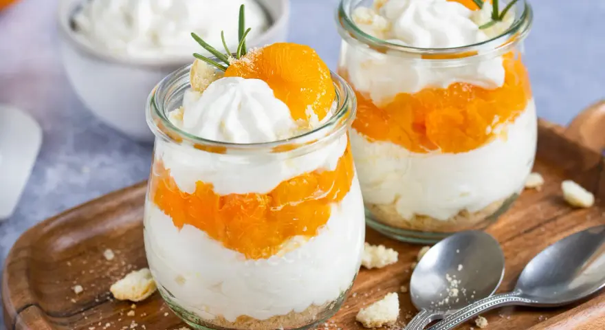 Zwei Gläser mit einem schnellen Dessert aus Mandarinen und Sahne, garniert mit Rosmarin.