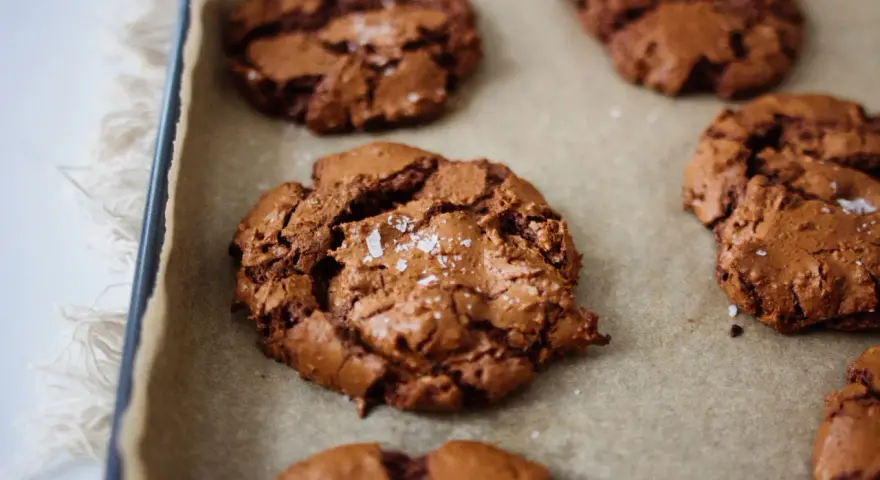 Saftige schoko cookies mit Meersalzflocken auf Backpapier, bereit zum Genießen.