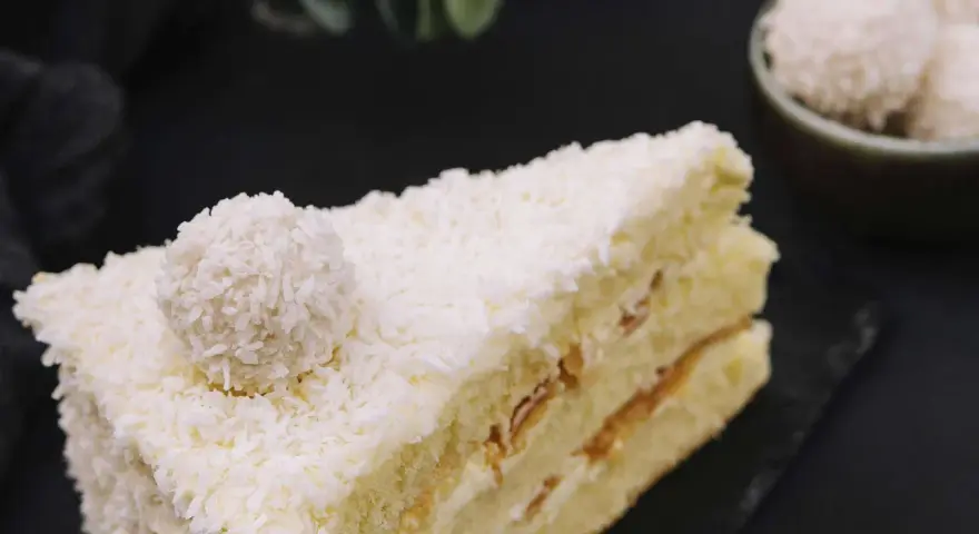 Ein Stück Raffaello Torte, bedeckt mit Kokosraspeln und einer Raffaello-Kugel.