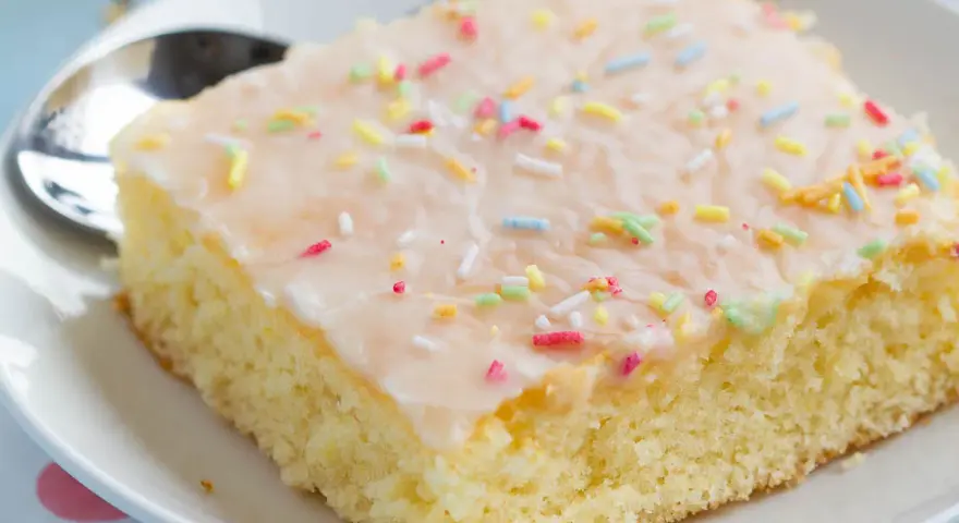 Ein Stück saftiger Fantakuchen mit Zuckerguss und bunten Streuseln, perfekt für das Fantakuchen Rezept.