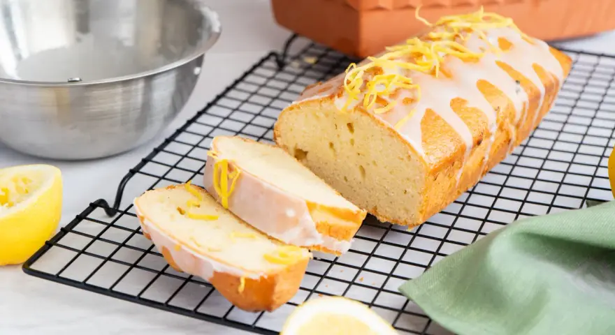 Ein saftiger Zitronenkuchen, frisch aus dem Ofen, mit Zuckerguss und Zitronenschale verziert. Perfekt für ein Zitronenkuchen Rezept.