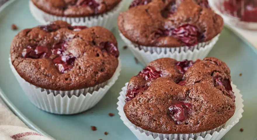 Saftige schoko kirsch muffins auf einem blauen Teller, bereit zum Genießen.