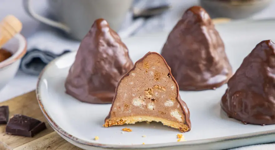 Schokoladen-Desserts, die an Granatsplitter erinnern, mit einem Stück, das die cremige Füllung mit Keksstücken zeigt. Ein köstliches granatsplitter rezept.