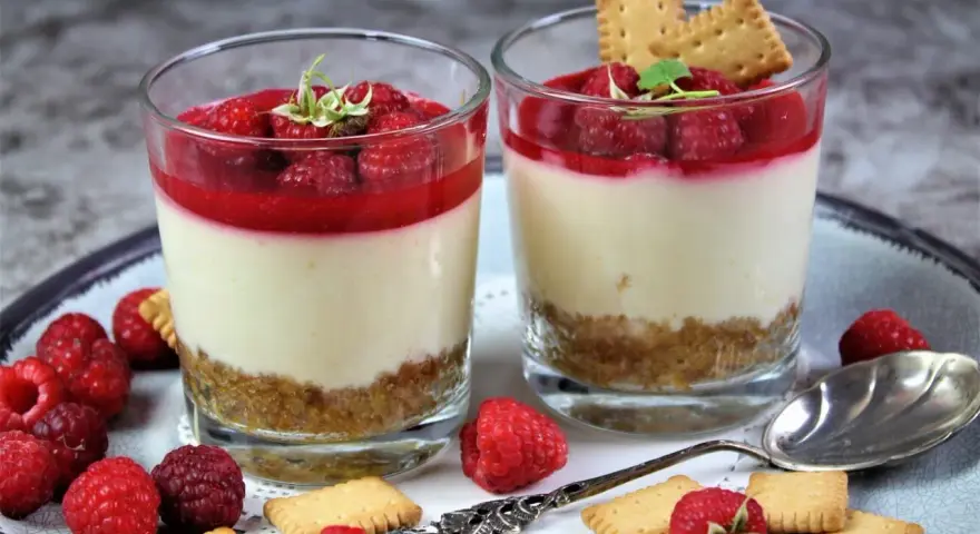 Zwei leckere Desserts im Glas mit Himbeeren und Keksen, ein süßer Genuss.
