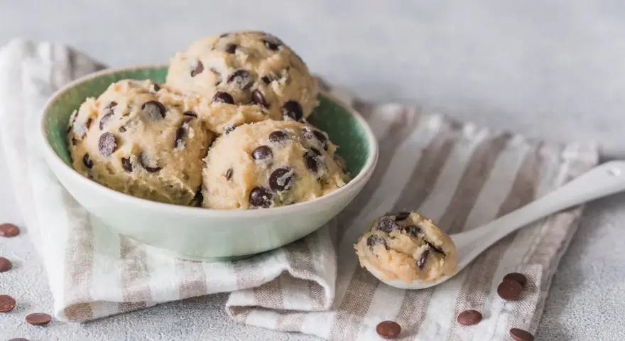 Schüssel mit Kugeln von Cookie Dough Rezept, Löffel mit Teig und Schokostückchen.