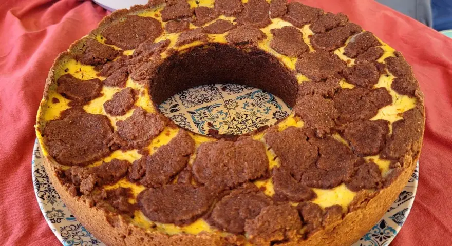 Ein köstlicher russischer Zupfkuchen mit einem Mürbeteigboden und einer cremigen Käsemasse, bedeckt mit schokoladigen Zupfen.
