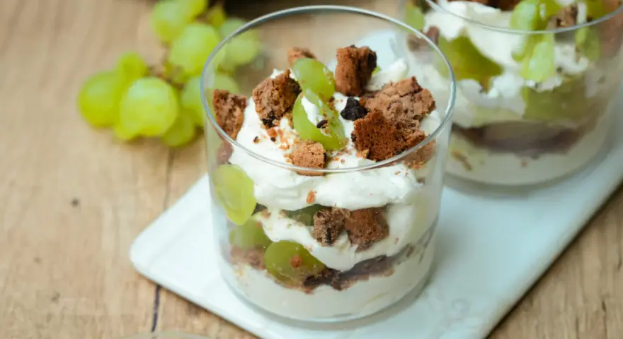 Cremiges Dessert im Glas mit grünen Trauben und zerbröselten Keksen. Ein süßer Genuss, der an einen Trauben-Keks-Traum erinnert.