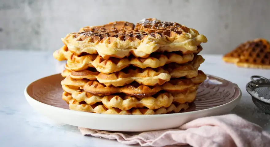 Ein Stapel goldbrauner Quarkwaffeln, bestäubt mit Puderzucker. Perfekt für ein schnelles Quarkwaffeln Rezept.