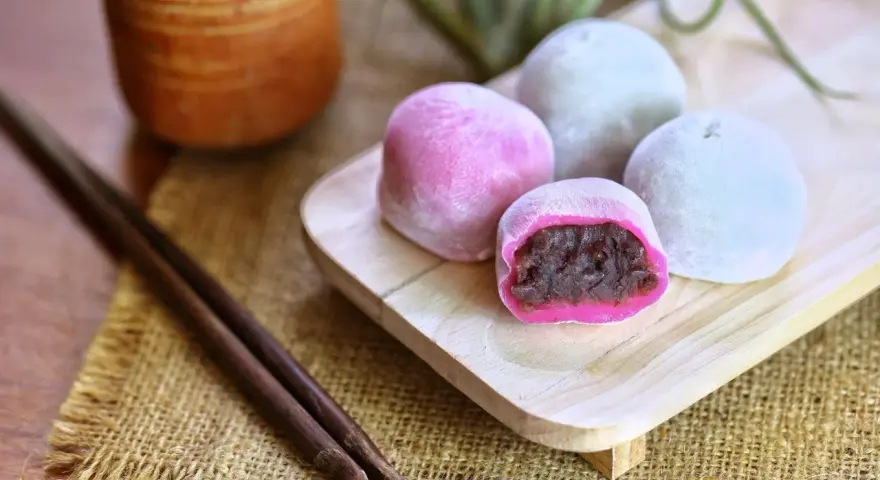 Bunte Mochi-Kugeln mit roter Bohnenpaste, bereit zum Genießen. Perfekt, um Mochi selber machen zu lernen und diese Leckereien zu kreieren.