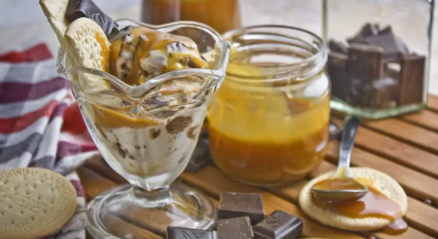 Eisbecher mit Karamellsauce, Keksen und Schokostückchen. Selbstgemachtes Karamell zum Verfeinern.