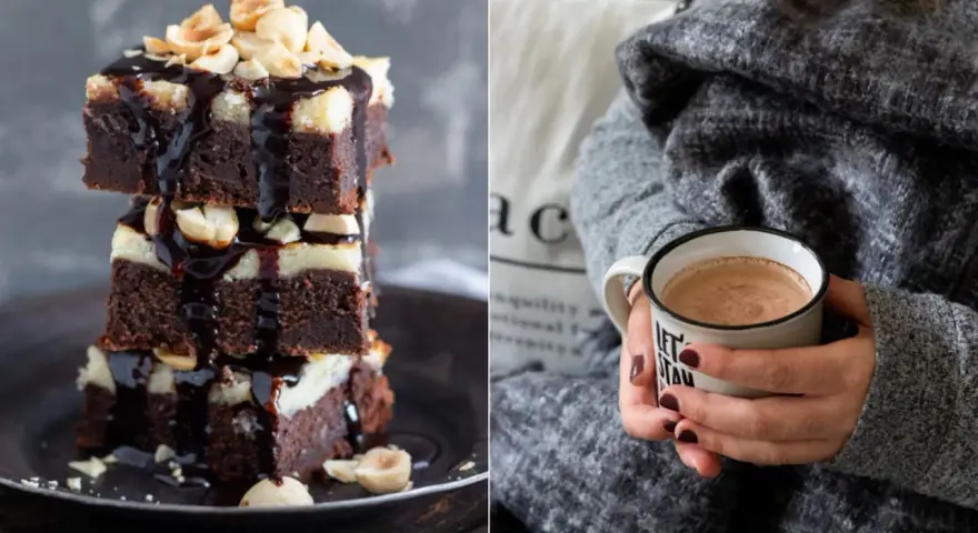 Gestapelte Cheesecake Brownies mit Schokoladenglasur und Nüssen, daneben eine Tasse Kakao.